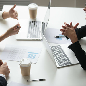 smiling-businesswoman-enjoying-talk-with-colleagues-during-teamwork-with-laptops.jpg